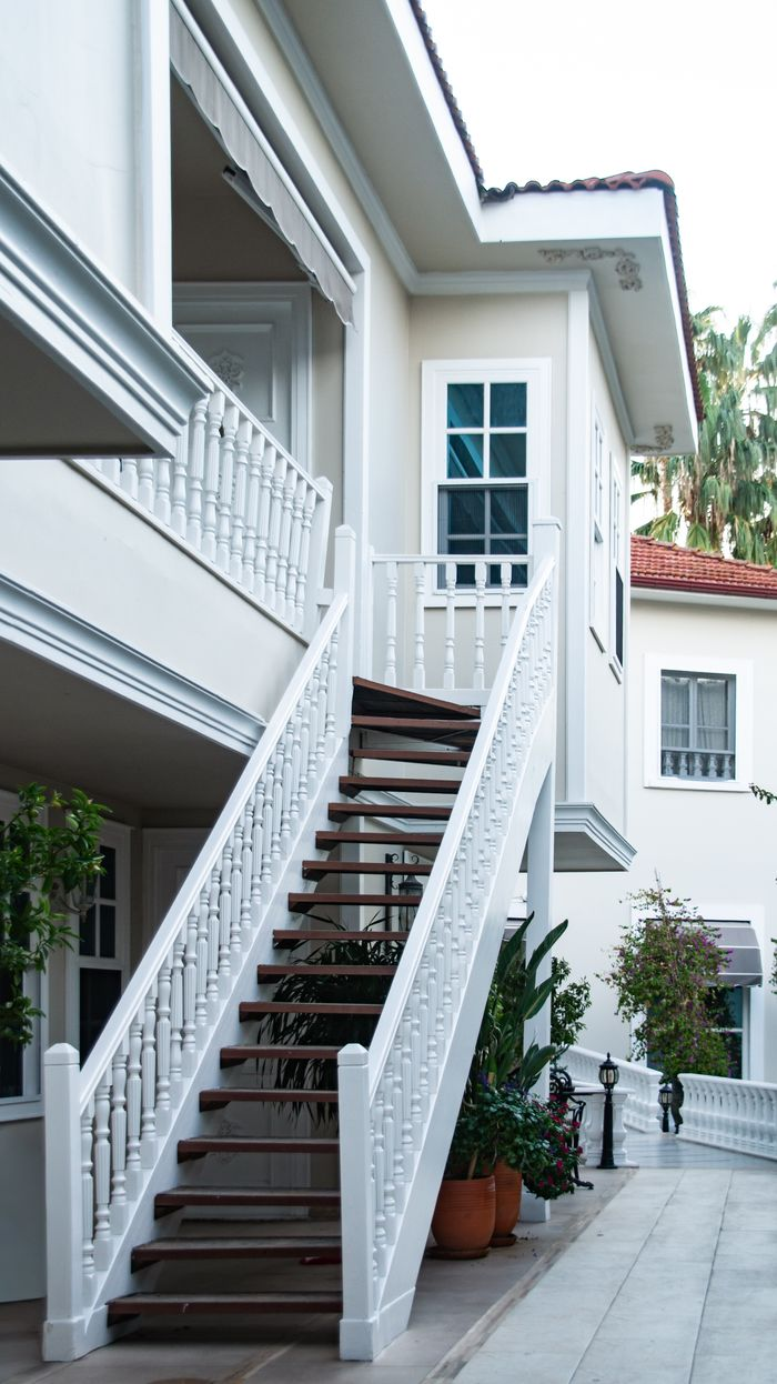 Stylish white staircase outside a contemporary villa with lush greenery and elegant design.